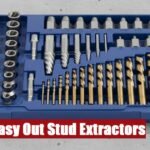 A metal toolbox containing an easy out stud extractor set lying flat on a rough gray cement surface.