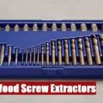 Open toolbox with a wood screw extractor set lying on a cement floor ready for professional repair work.